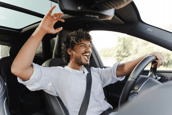 A smiling driver holding a steering wheel representing insurance savings